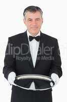 Smiling waiter looking at camera while holding a silver tray