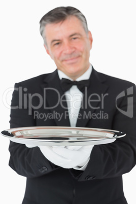 Smiling waiter holding a silver tray with both hands