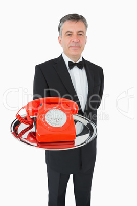 Well-dressed waiter holding a phone on a silver tray