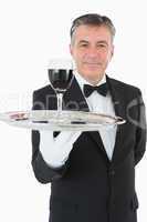 Cheerful waiter holding a glass of wine on a silver tray