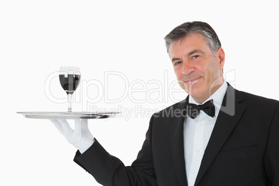 Smiling waiter holding a glass of wine on a silver tray