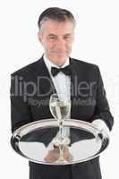 Smiling waiter serving glass of wine on tray