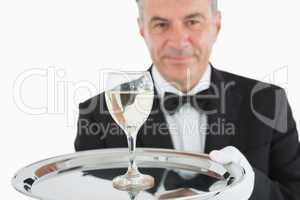 Smiling man serving glass of wine on platter
