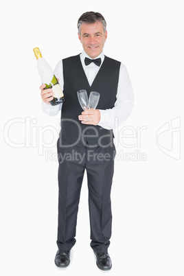 Smiling waiter holding glasses and champagne bottle