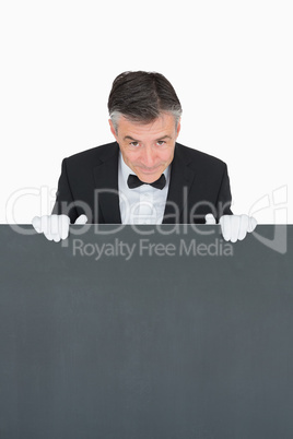 Smiling waiter behind grey board