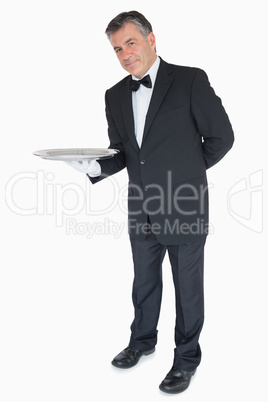 Waiter with his hand behind his back showing an empty tray