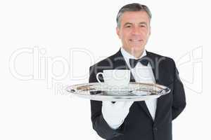 Smiling waiter holding tray with coffee cup