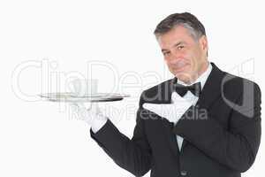 Waiter showing silver tray with cup