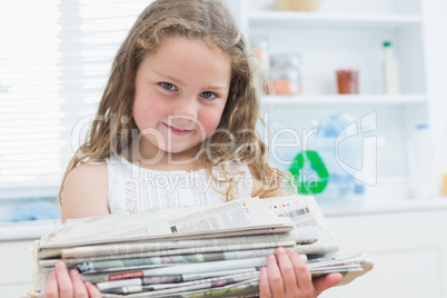 Girl holding old newspapers in the kitchen