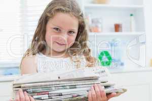 Girl holding old newspapers in the kitchen