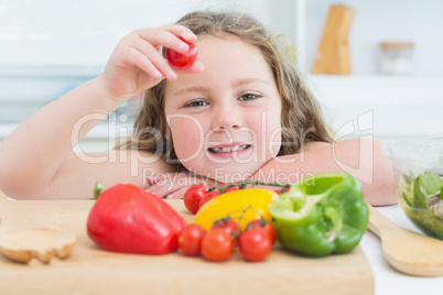 Little girl holding up cherry tomato