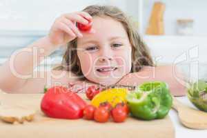 Little girl holding up cherry tomato