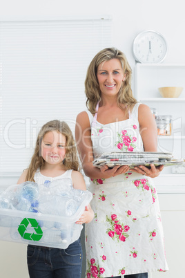 Mother and daughter standing in the kitchen with waste for recyc