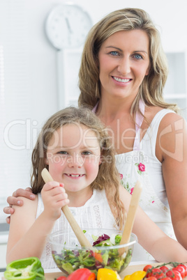 Daughter and mother making salad while looking into the camera