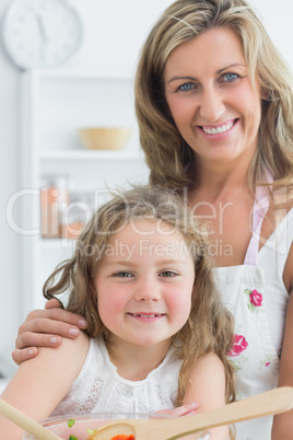 Mother hugging daughter and making salad