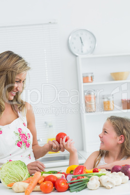 Daughter giving tomato to mother