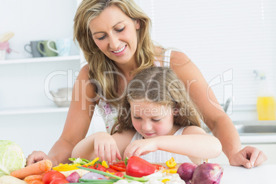 Mother teaching her daughter how to prepare vegetables