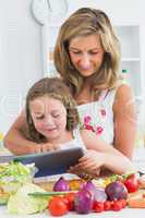 Smiling mother and daughter using tablet
