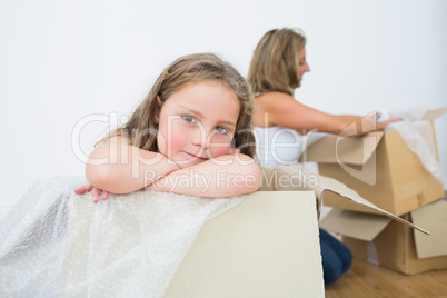 Daughter sitting in the box while her mother unpacking something