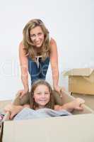 Daughter laying in the box while her mother bows over her