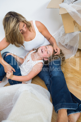 Laughing mother and daughter sitting on the floor