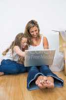 Smiling mother and daughter sitting on the floor