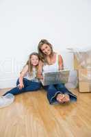 Smiling daughter and mother sitting on the floor