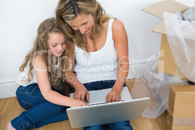 Smiling mother and daughter using laptop