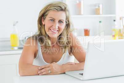 Woman sitting in the kitchen and using laptop