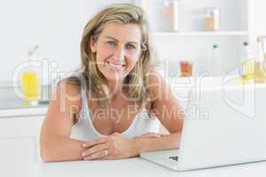 Woman sitting in the kitchen and using laptop