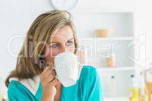 Woman in dressing gown sitting in the kitchen and drinking