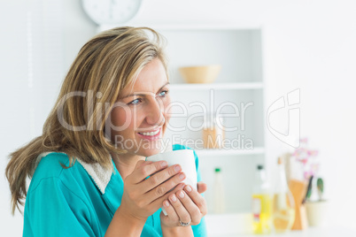 Smiling woman holding mug and wearing bathrobe