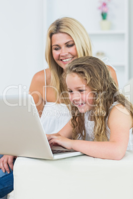 Mother and daughter sitting on the sofa with laptop