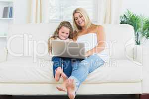 Daughter and mother resting on the sofa with laptop