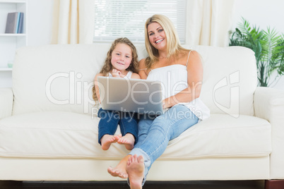 Daughter and mother relaxing on the sofa with notebook