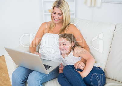 Laughing mother and daughter using notebook