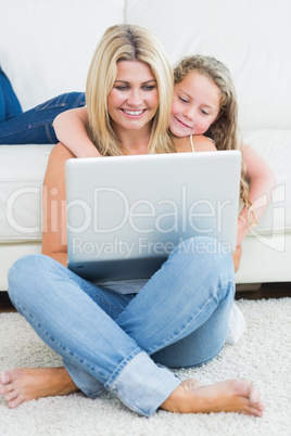 Mother sitting on the floor while her daughter hugging her from