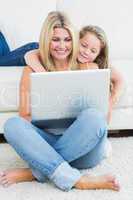 Mother sitting on the floor while her daughter hugging her from