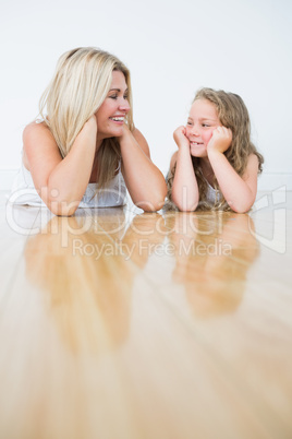 Smiling daughter and mother laying on the floor