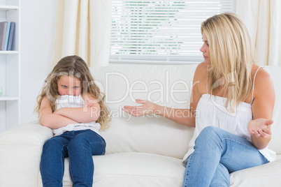 Angry mother sitting with her daughter on the sofa