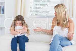 Angry mother sitting with her daughter on the sofa