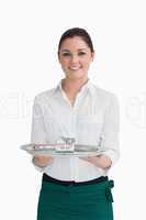 Waitress presenting miniature house on tray