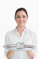 Smiling waitress holding tray with miniature house