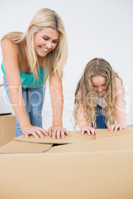 Mother and daughter closing moving boxes