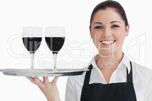 Happy waitress holding two glass of wine