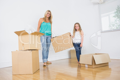 Mother and daughter carrying moving boxes