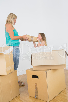 Smiling mother and daughter holding moving box