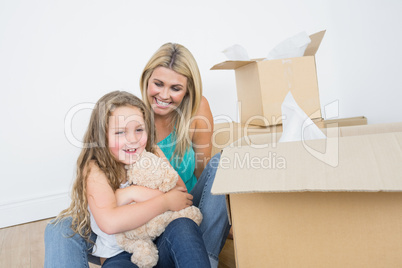 Child holding a teddy bear near her mother
