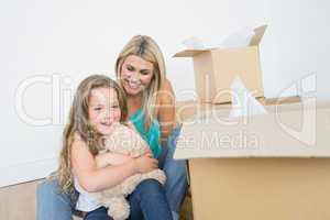 Child holding a teddy bear near her mother