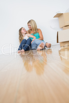Smiling mother and daughter sitting on floor Smiling mother and daughter sitting on floor